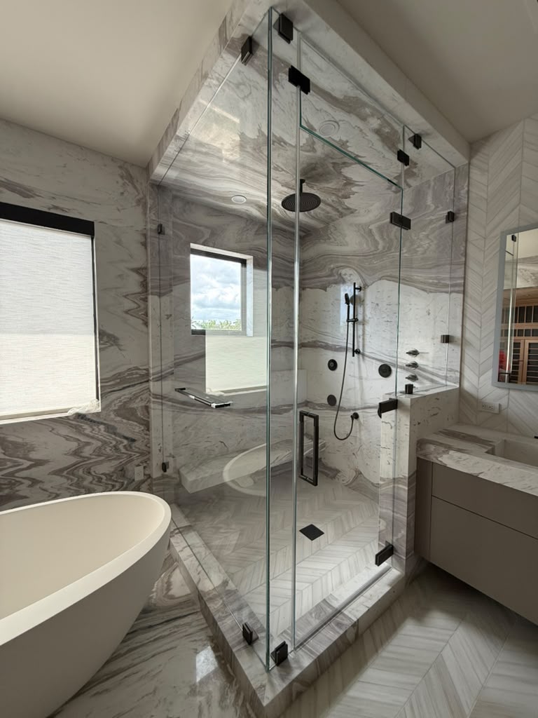 Finished glass shower enclosure with black hardware and marble surround
